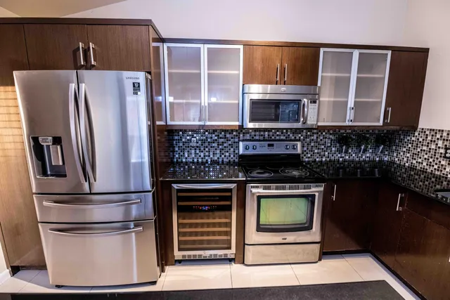 a kitchen with stainless steel appliances kitchen island granite countertop a refrigerator and a stove top oven