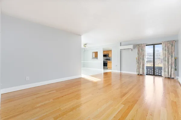 a view of an empty room with wooden floor and a window