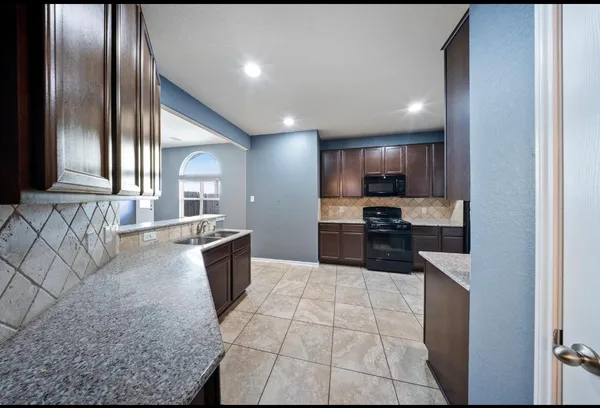 a large kitchen with a large counter top stainless steel appliances and cabinets