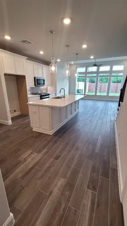 a large kitchen with stainless steel appliances a large counter top a stove and a wooden floors