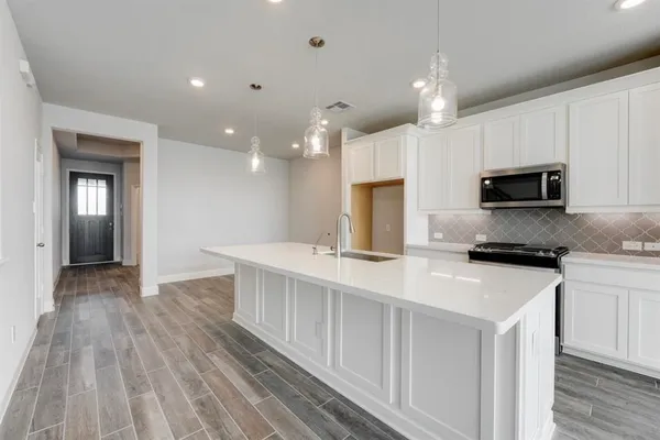 a kitchen with kitchen island a sink dishwasher a stove and a microwave oven with wooden floor