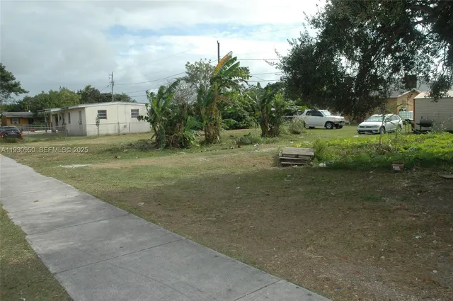 a view of a white house next to a yard with big trees