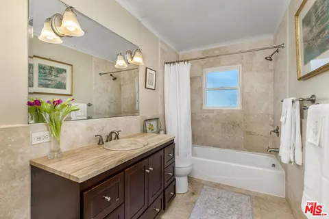 a bathroom with a granite countertop sink a mirror a bathtub and shower