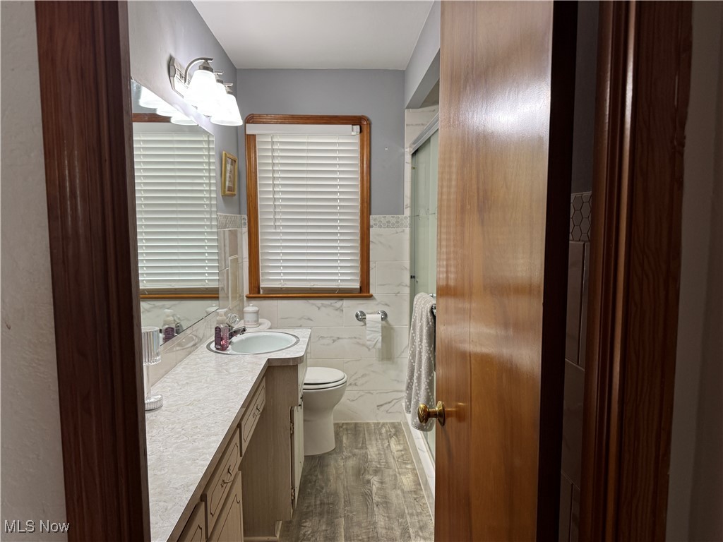 5544 Hauserman Road Cleveland, OH 44130 - Photo 25 of 41 Full bath with vanity, tile walls, dark wood-style flooring, a stall shower, and a wainscoted wall
