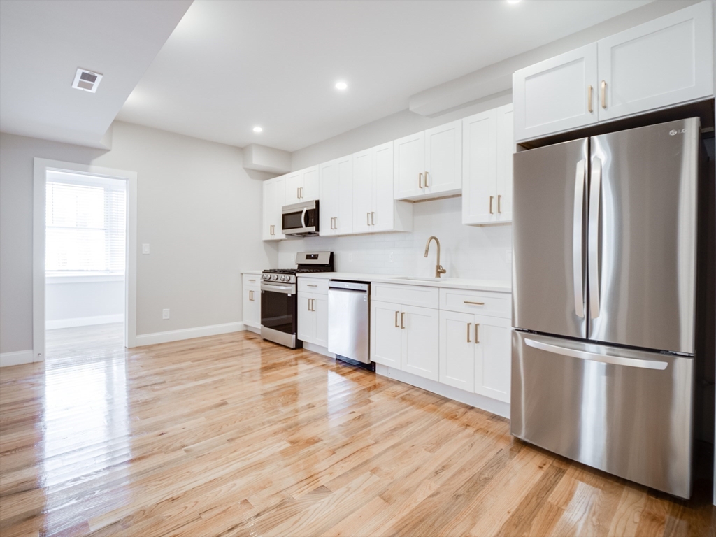232 Saratoga Street, Unit 2 Boston, MA 02128 - Photo 3 of 9 a kitchen with white cabinets and stainless steel appliances