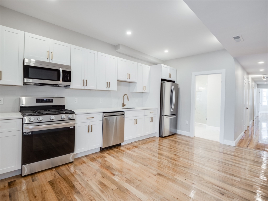 232 Saratoga Street, Unit 2 Boston, MA 02128 - Photo 4 of 9 a kitchen with stainless steel appliances granite countertop a stove a sink and a refrigerator