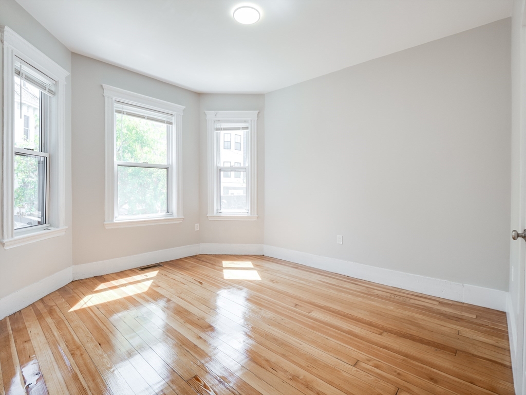 232 Saratoga Street, Unit 2 Boston, MA 02128 - Photo 6 of 9 an empty room with wooden floor and windows