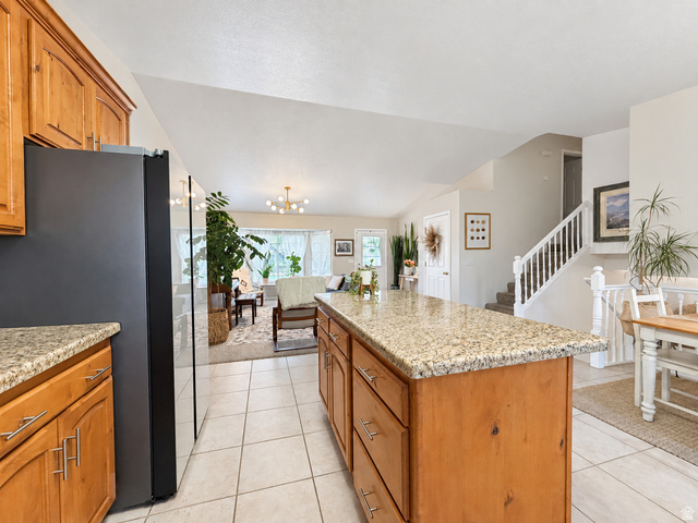 Kitchen island featuring a granite-style countertop, wood-finish cabinetry, and tile flooring