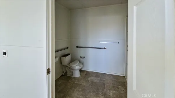 a white toilet sitting next to a white wall