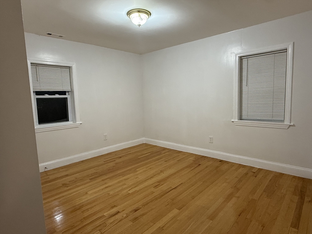 23 Myrtle Street, Unit 2 Quincy, MA 02171 - Photo 7 of 12 an empty room with wooden floor and windows
