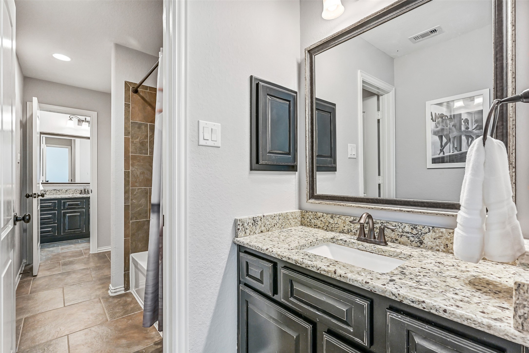1008 Point Isabel Lane Friendswood, TX 77546 - Photo 40 of 50 The Jack & Jill style upstairs bath features dual granite countertops with rectangular basin sinks and framed mirrors, updated fixtures, a combination tub/shower with tile walls, and a clean, neutral palette that complements the home’s overall style.