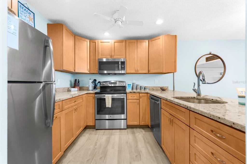 102 68th Street, Unit 102 Holmes Beach, FL 34217 - Photo 16 of 48 a kitchen with stainless steel appliances granite countertop a refrigerator sink and cabinets