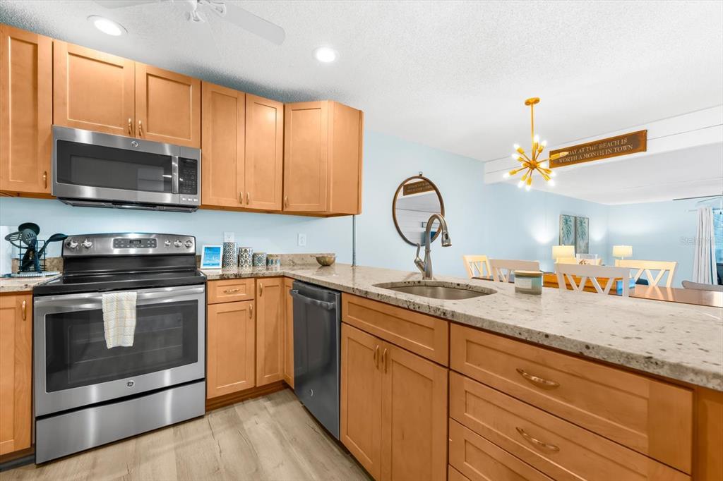 102 68th Street, Unit 102 Holmes Beach, FL 34217 - Photo 17 of 48 a kitchen with stainless steel appliances granite countertop a sink a stove and a microwave oven with cabinets