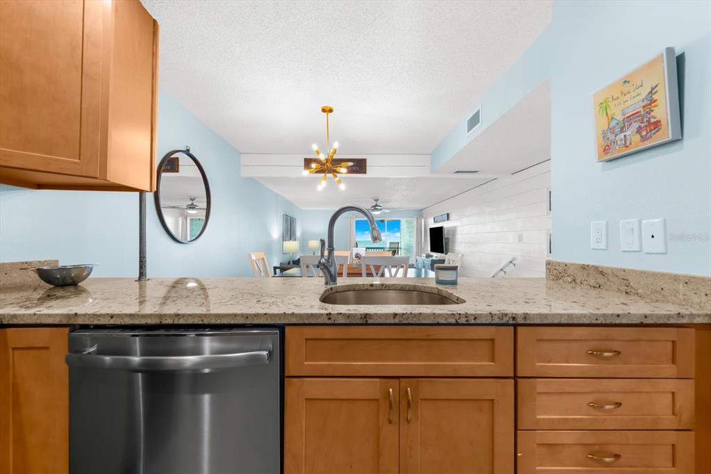 102 68th Street, Unit 102 Holmes Beach, FL 34217 - Photo 18 of 48 a kitchen with granite countertop a sink and a clock on the wall