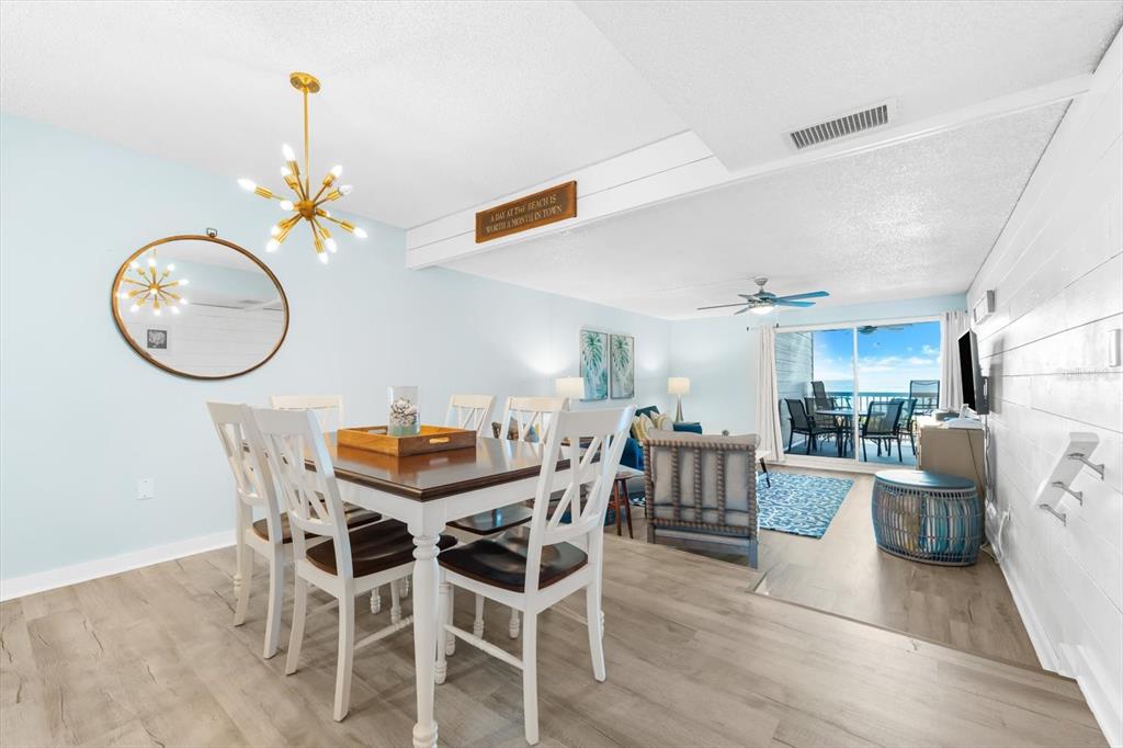 102 68th Street, Unit 102 Holmes Beach, FL 34217 - Photo 19 of 48 a view of a dining room with furniture a chandelier and wooden floor