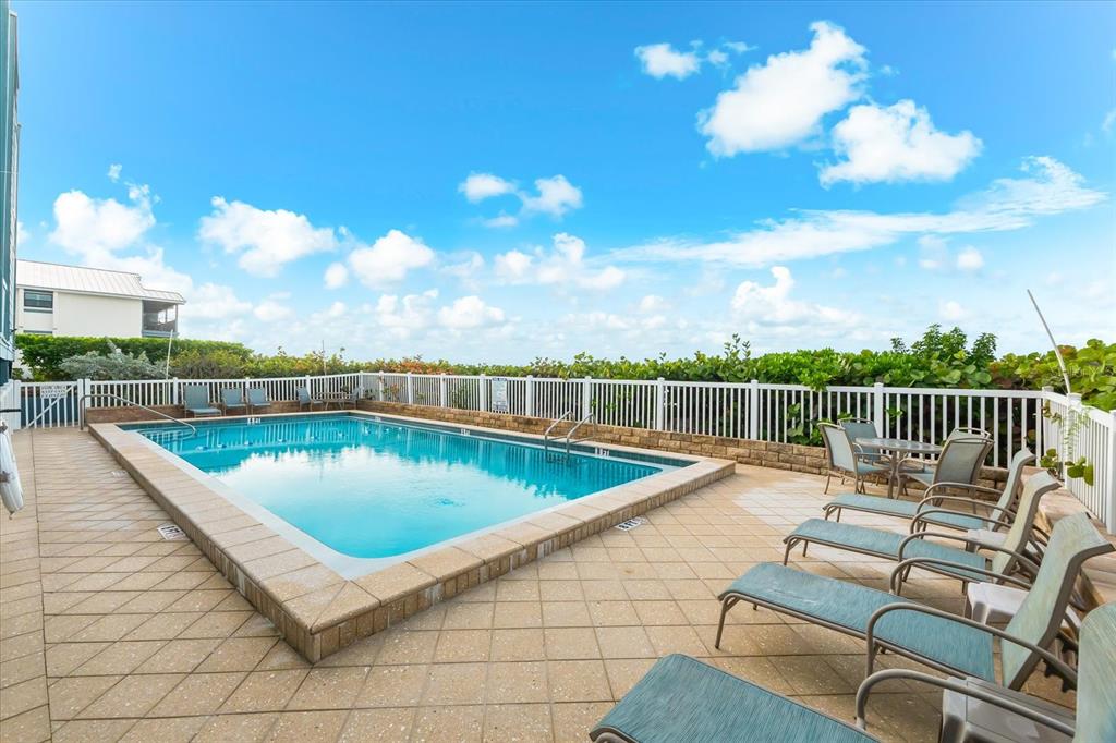 102 68th Street, Unit 102 Holmes Beach, FL 34217 - Photo 32 of 48 a view of a swimming pool with a lounge chair