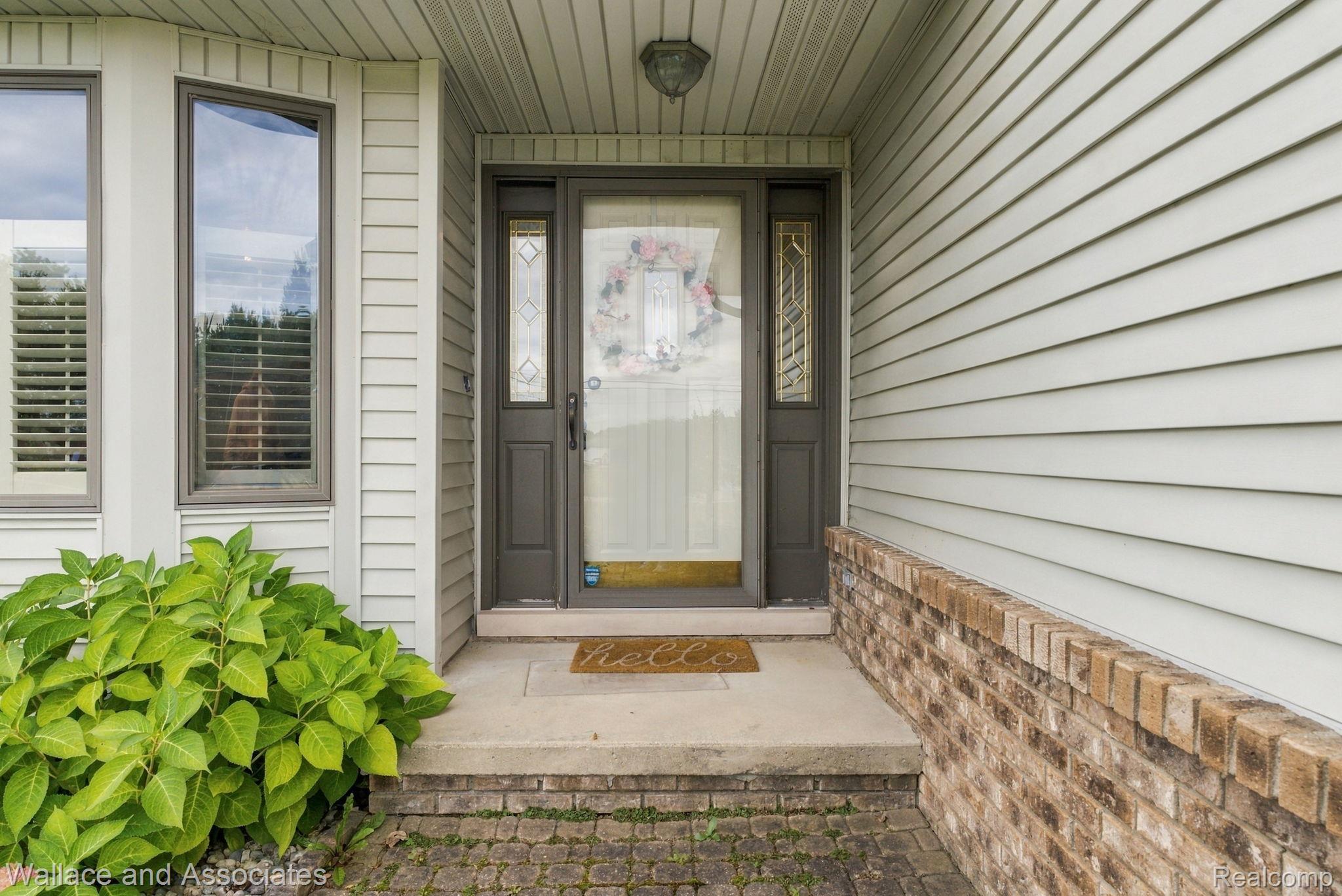 17076 27 Mile Road Ray, MI 48096 - Photo 6 of 63 Entryway featuring a dark-framed glass panel door with sidelights, bay windows, light-colored siding, and a brick facade