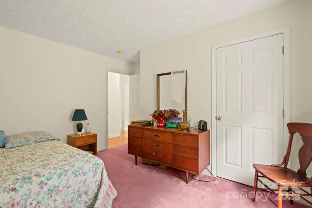 a bedroom with a bed table flowerpot and window