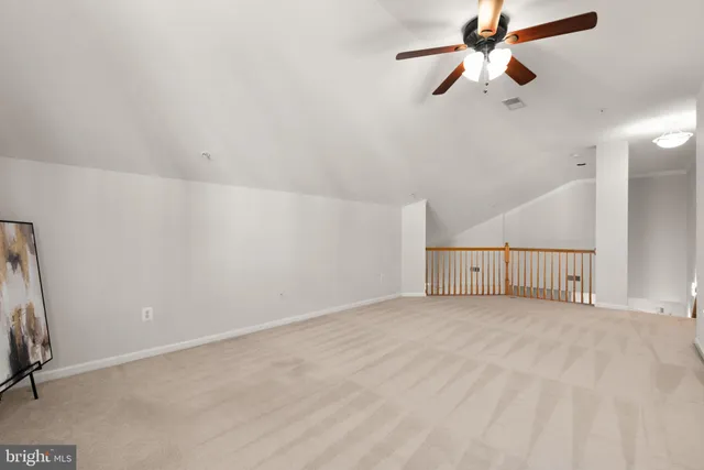 an empty room with chandelier fan and windows