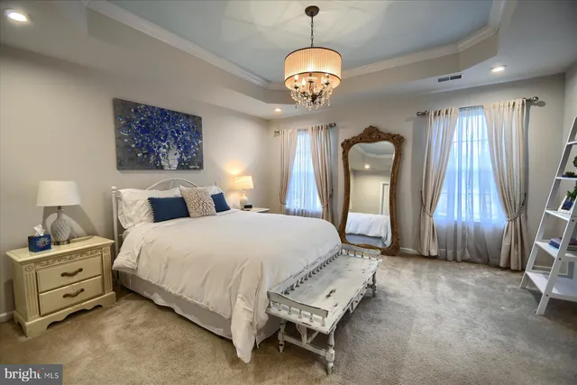 a bedroom with a bed a chandelier and dresser