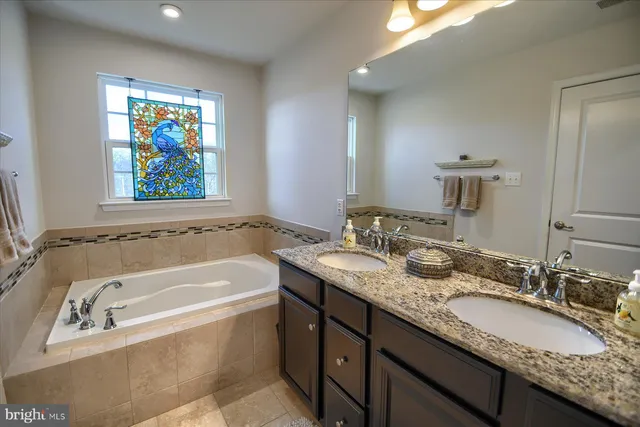 a bathroom with a granite countertop tub sink and mirror
