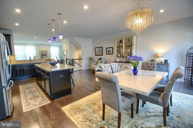 a kitchen with stainless steel appliances kitchen island granite countertop a table chairs and a refrigerator