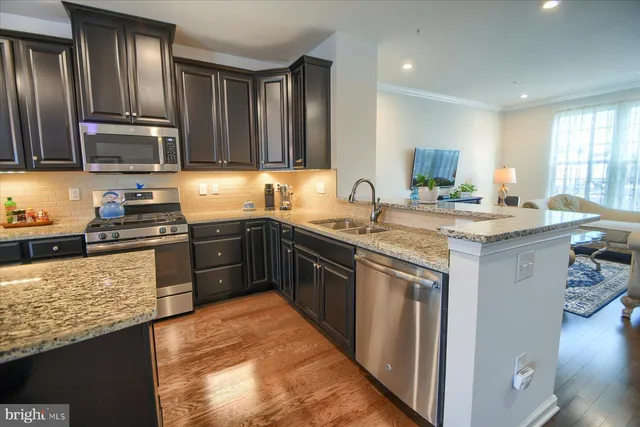 a kitchen with stainless steel appliances granite countertop a sink stove microwave and refrigerator