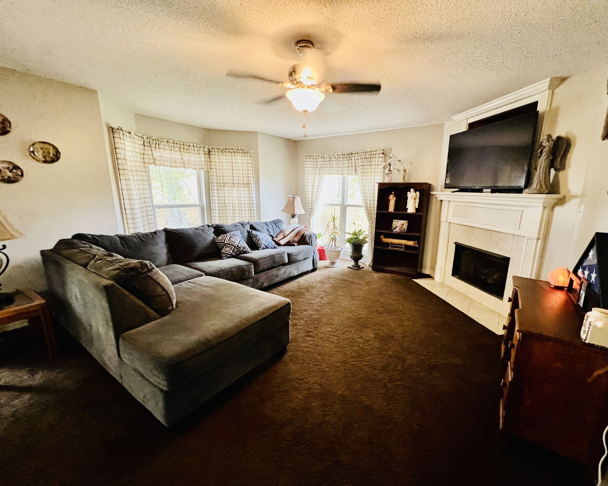 The living area has windows that give lots of light, the fireplace has gas logs, and a ceiling fan.