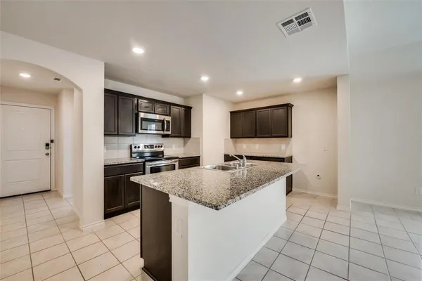 a kitchen with stainless steel appliances granite countertop a sink and a refrigerator