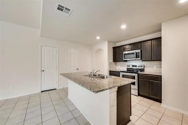 a kitchen with stainless steel appliances granite countertop a stove a sink and a refrigerator