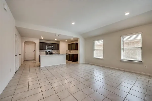 a view of empty room with kitchen and window