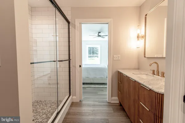 a bathroom with a granite countertop sink a mirror and shower