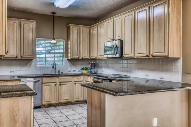 en empty room with windows and a chandelier fan