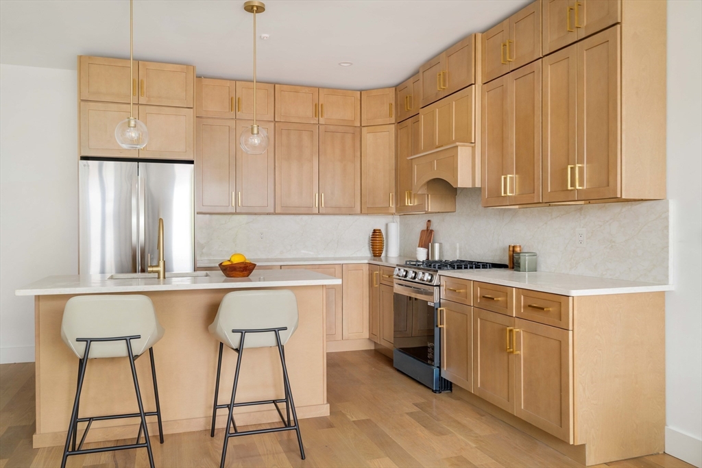 95 Addison Street, Unit A Boston, MA 02128 - Photo 10 of 12 a kitchen with stainless steel appliances a stove a sink cabinets and a refrigerator