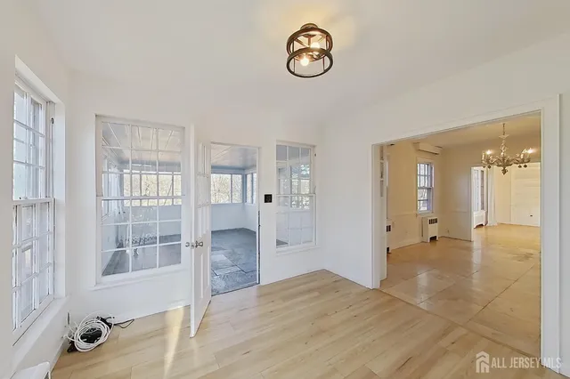 a view of a hallway with wooden floor and a bathroom