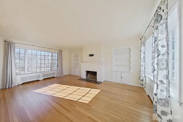 a view of empty room with fireplace and wooden floor