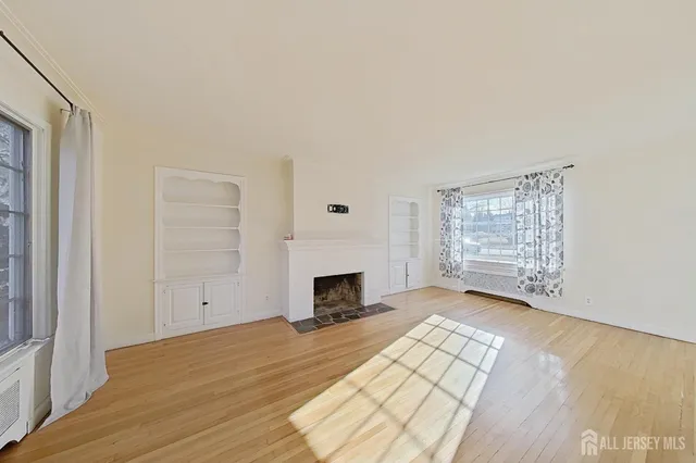 an empty room with windows fireplace and wooden floor