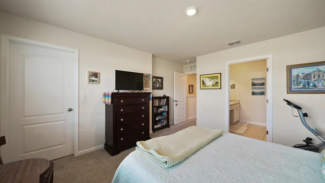 a bedroom with a bed and a flat tv screen on the dresser