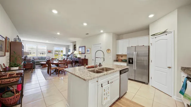 a kitchen with stainless steel appliances granite countertop a refrigerator oven stove a sink a dining table and chairs with wooden floor