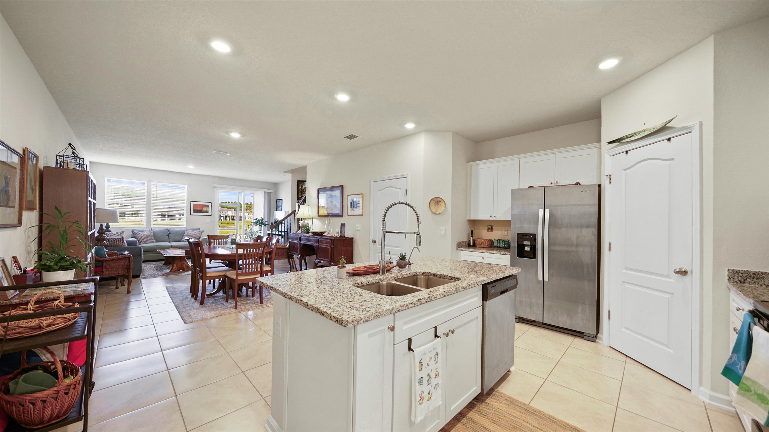 194 Redbud Road Palm Coast, FL 32137 - Photo 5 of 34 a kitchen with stainless steel appliances granite countertop a refrigerator oven stove a sink a dining table and chairs with wooden floor