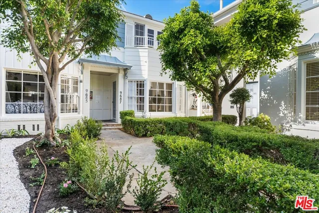 a front view of a house with garden and trees