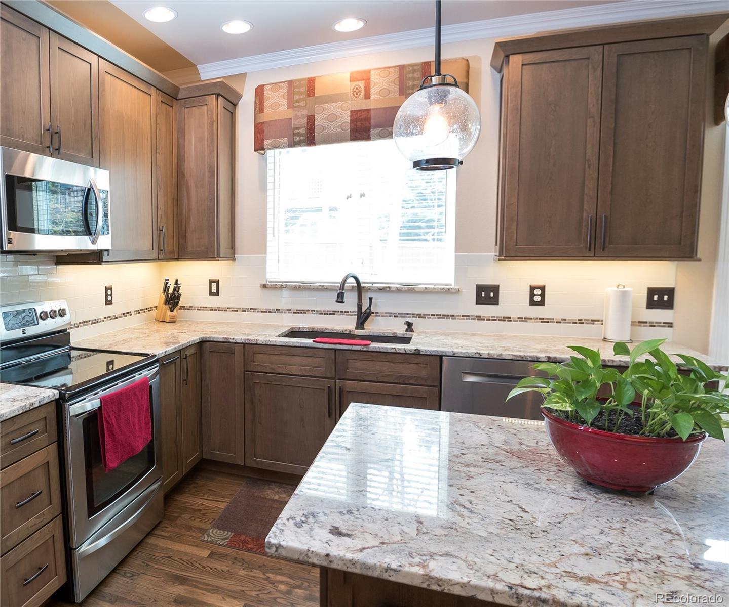 10221 South Nickolas Avenue Highlands Ranch, CO 80130 - Photo 8 of 35 a kitchen with kitchen island granite countertop a sink stainless steel appliances and cabinets