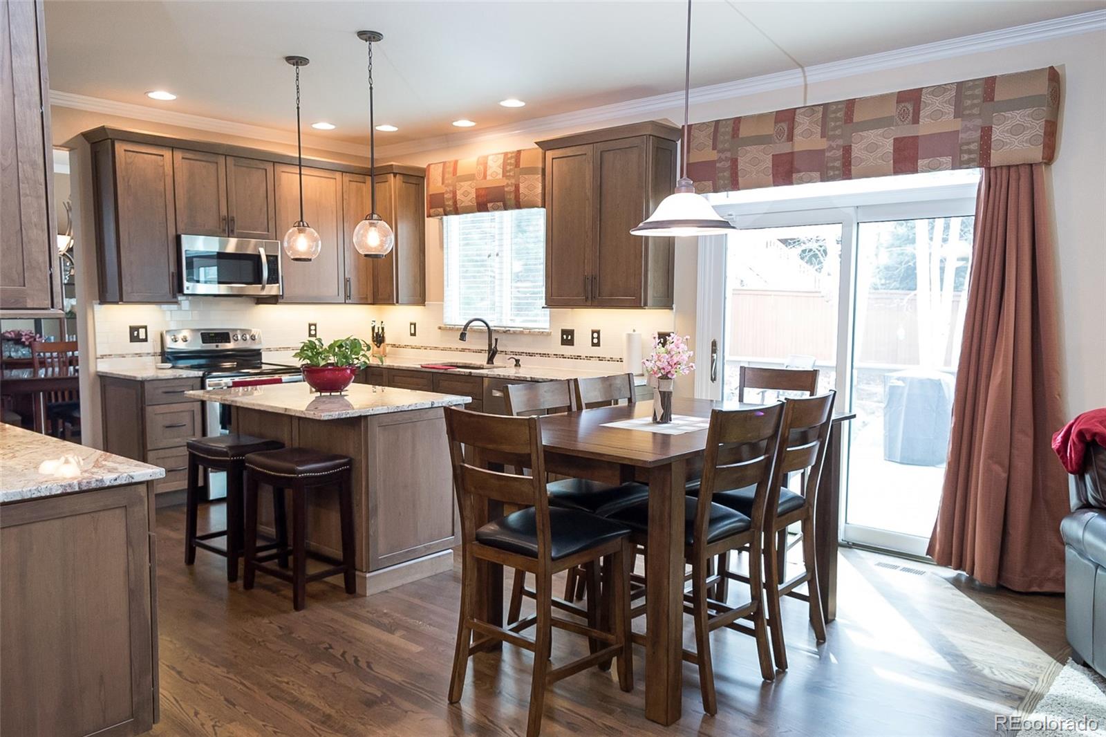10221 South Nickolas Avenue Highlands Ranch, CO 80130 - Photo 10 of 35 a kitchen with a dining table chairs and white cabinets