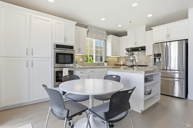 a kitchen with refrigerator a sink and chairs