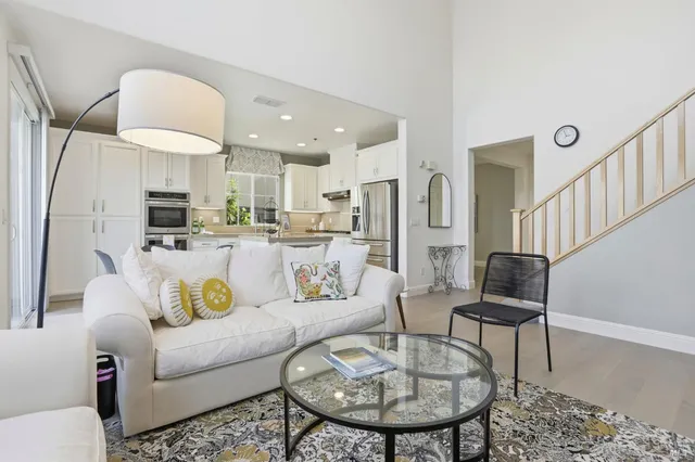 a living room with stainless steel appliances furniture a rug and a view of kitchen