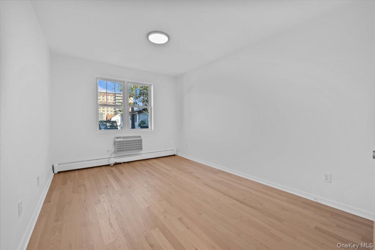 126 Beach 92nd Street, Unit 3C Queens, NY 11693 - Photo 6 of 16 an empty room with wooden floor and windows