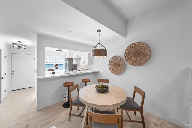 a dining room with wooden floor chairs and kitchen view