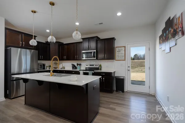 a kitchen with stainless steel appliances granite countertop a refrigerator a sink dishwasher a stove and a oven with wooden floor