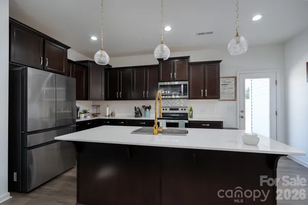 a kitchen with stainless steel appliances a sink stove refrigerator and cabinets