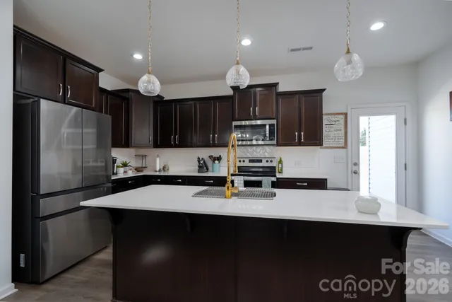 a kitchen with stainless steel appliances a sink stove refrigerator and cabinets